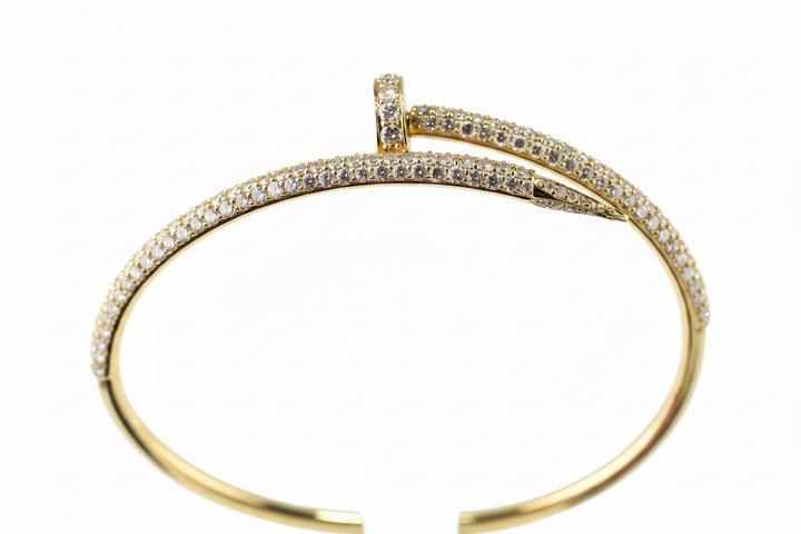 A gold hinged cuff bracelet with pavé-set clear stones, displayed on a white background.